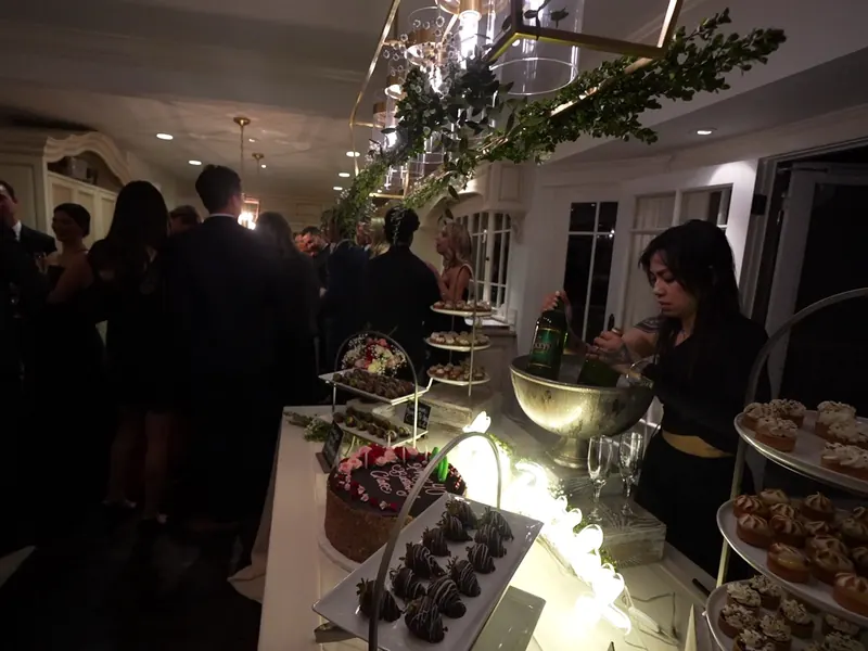 Tiered dessert and appetizer stands surrounded by guests at a Milpitas party