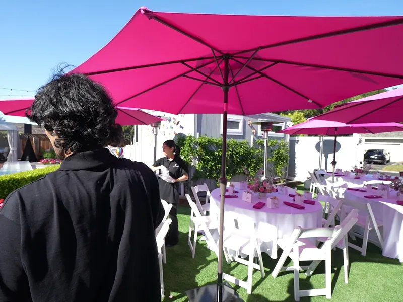 Pink market umbrellas shading round guest tables on a Hayward lawn