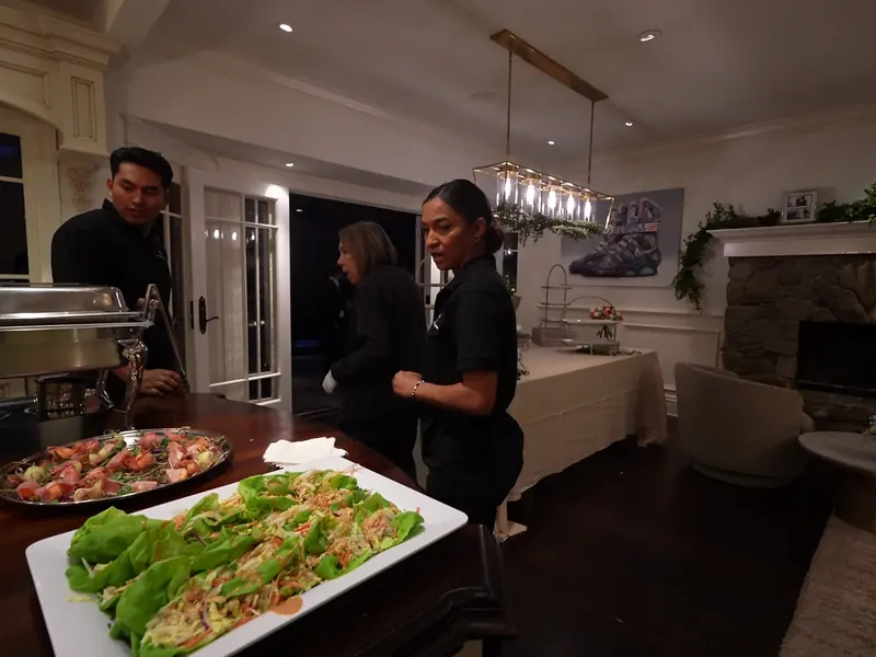 Catering team plating lettuce-wrap platters in the kitchen before a Newark event