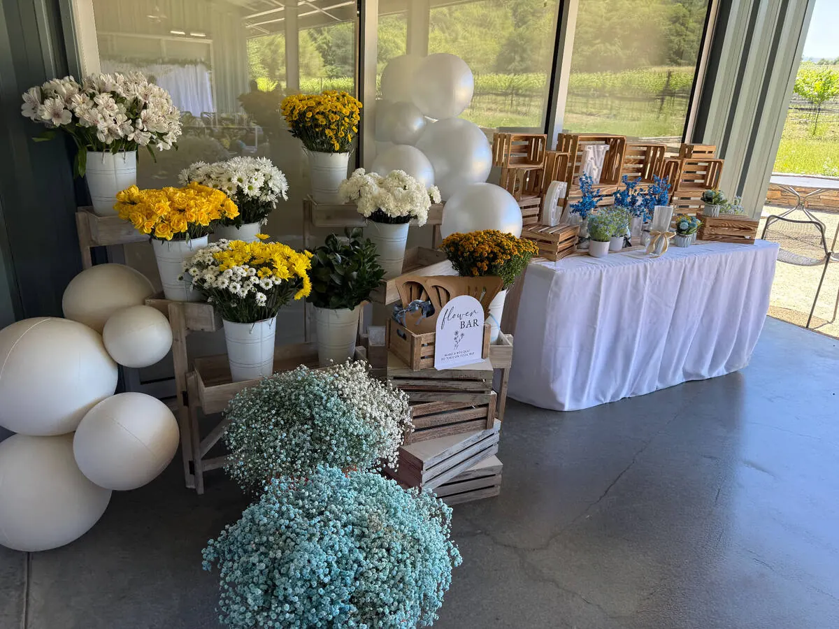 Guest-serve bloom bar stocked with yellow roses, daisies and baby's breath plus wrapping and ribbon — signature bloom bar from Fremont catering