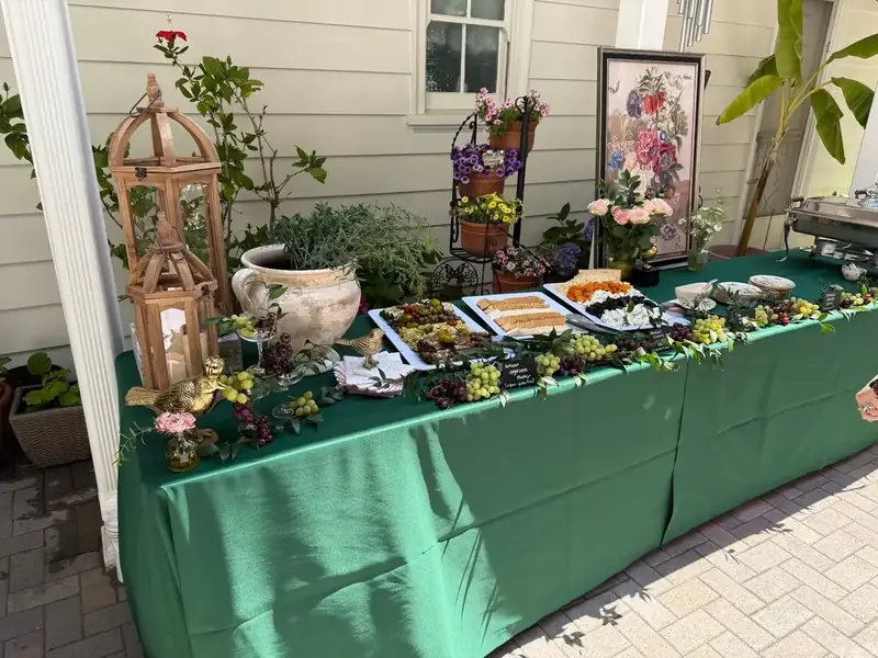 Fremont Catering Company’s outdoor grazing table arranged with artisan cheeses, grapes, appetizers, fresh flowers, and garden-inspired décor.